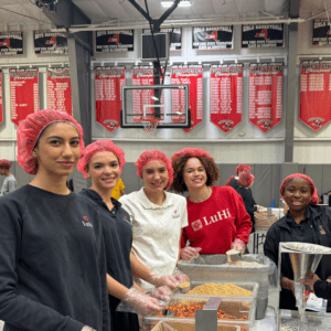 5 students smiling for photo during meal packing